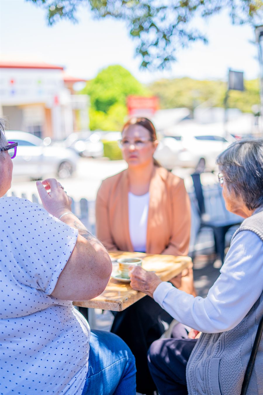 A support worker sharing coffee and a chat with clients at a local café