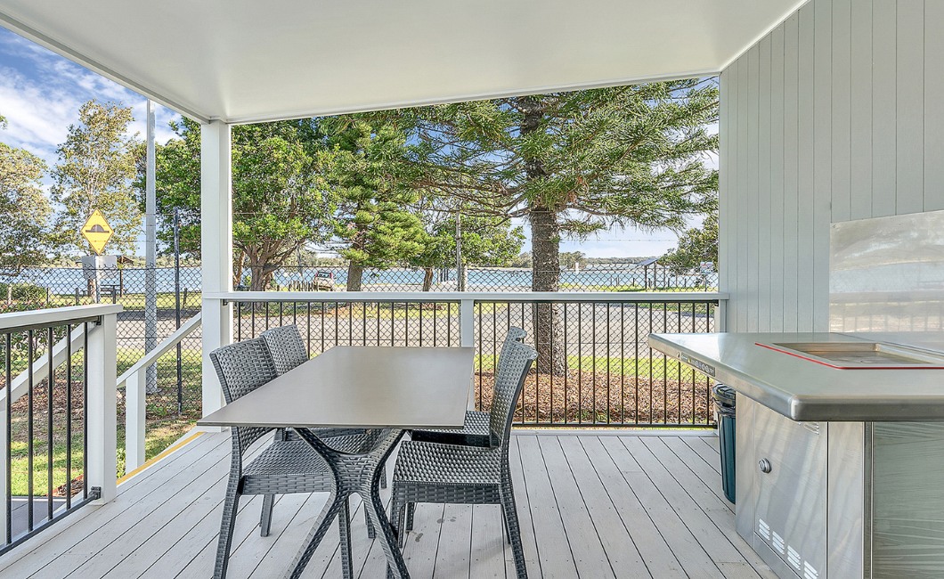The deck of a comfortable waterside cabin with an outdoor dining table